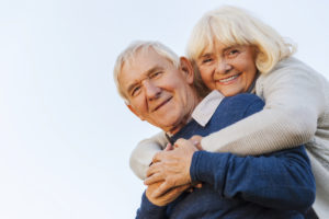 Forever young. Low angle view of happy senior couple bonding to each other and smiling with blue sky as background